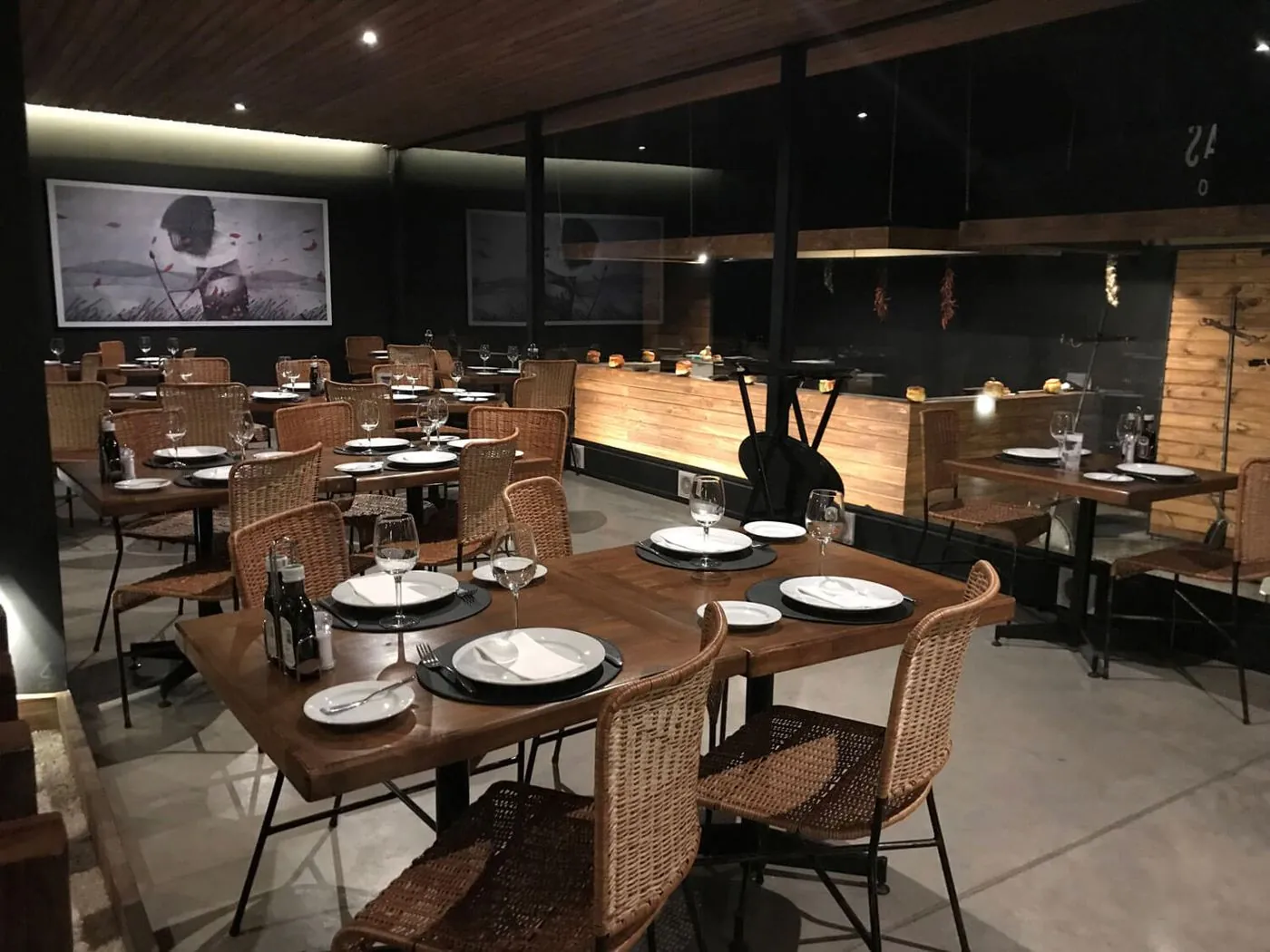 El salón parrilla vacío, con mesas de madera y sillas de ratán.