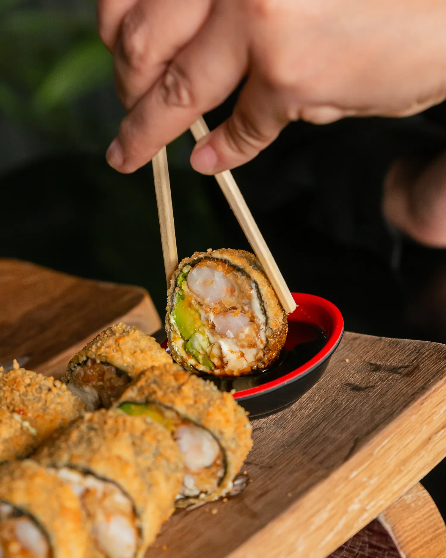 Unos palillos levantan una pieza de un roll apanado.